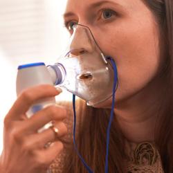 Woman inhaling from a mask nebulizer