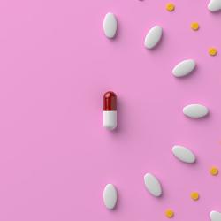 Pills and a capsule on pastel pink colored background. 3D rendered image.