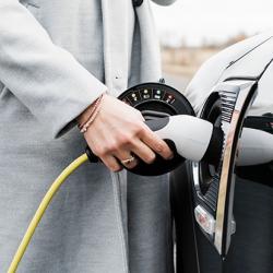 View of woman's hand plugging in charging lead to her electric car