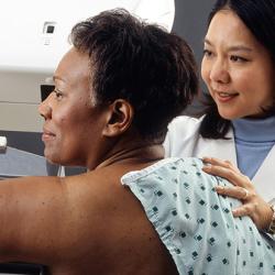 Female doctor standing near woman patient doing breast cancer