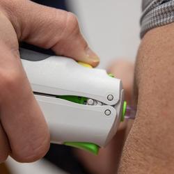 Vaccine being administered by needle-free injection into a volunteer's arm