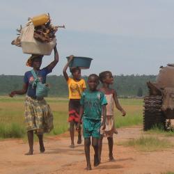 Angolan civilians walking past the remains of tanks in 2004. Relics of the conflict still litter the Angolan countryside.