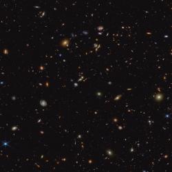 The image shows a deep galaxy field, featuring thousands of galaxies of various shapes and sizes. A cutout indicates a particular galaxy, known as JADES-GS-z6, which was a research target for this result. It appears as a blurry smudge of blue, red and green.